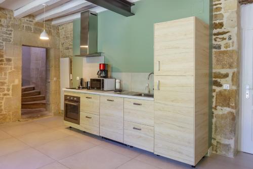 a kitchen with wooden cabinets and a sink at La Maison des mariés - Nature & Sèvre Niortaise in Sciecq