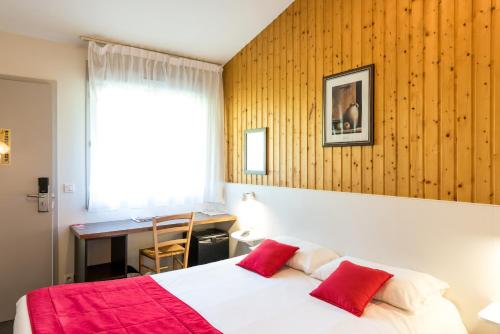 a bedroom with a bed with red pillows and a desk at Fasthotel Thones in Thônes