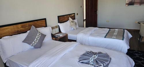 two beds in a hotel room with white sheets at Cornerstone Hotel Arusha in Arusha