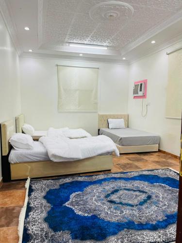 two beds in a room with a blue rug at اجنحة رحال لشقق الفروشة in Medina