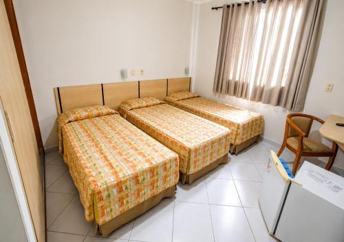 a hotel room with two beds and a table at SG Palace Hotel in Taubaté