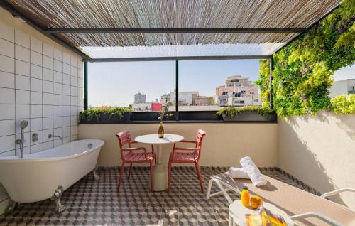 a bathroom with a bath tub and a table and chairs at Scarlet Hotel in Tel Aviv