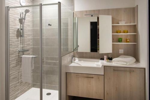 a bathroom with a shower and a sink and a glass shower stall at Domitys - Galilée in Cergy