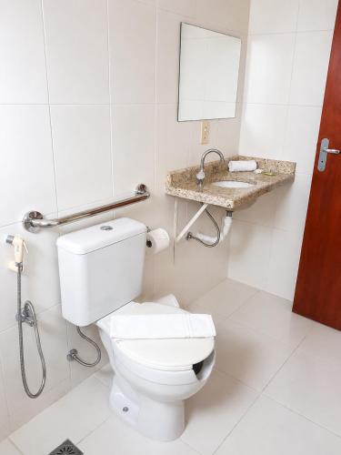 a bathroom with a toilet and a sink at SG Palace Hotel in Taubaté