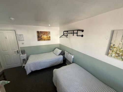 a room with two beds in a room with a door at The Pickwick Inn in Kingsbridge