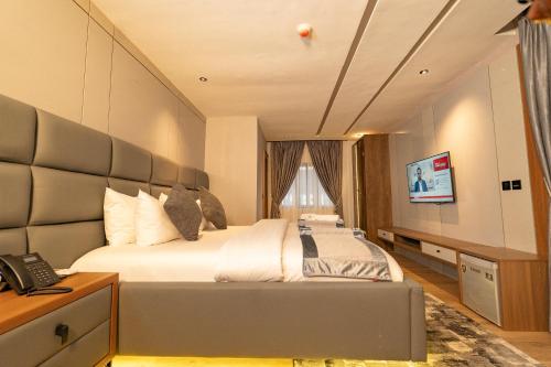 a bedroom with a large bed and a television at Grande Candor Exclusive Hotel in Warri Airport