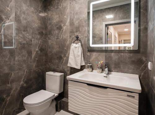 a bathroom with a toilet and a sink and a mirror at Avangard Hotel in Almaty