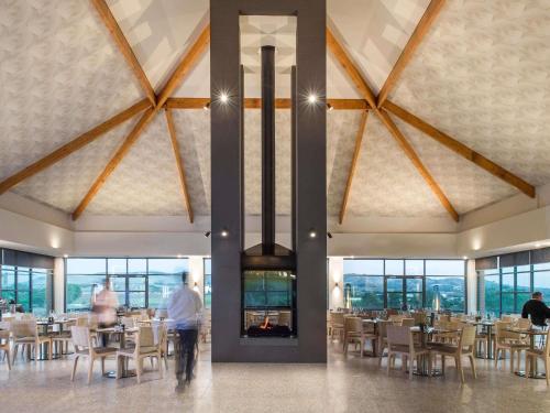 a dining room with tables and chairs in a building at Novotel Barossa Valley Resort in Rowland Flat