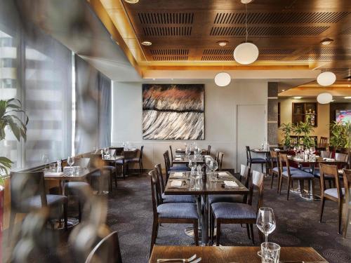 a restaurant with tables and chairs and a painting on the wall at Novotel Wellington in Wellington