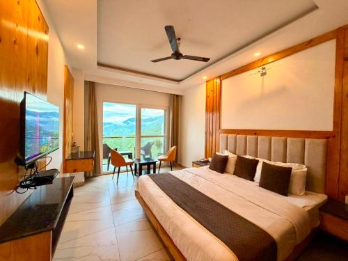 a bedroom with a large bed with a ceiling fan at Pine View Luxury Resort With Mountain View & Premium Rooms Mussoorie in Mussoorie