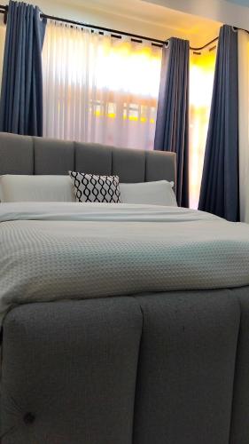a large bed in a bedroom with blue curtains at Vito Haven suites in Busia