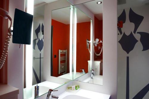a bathroom with a sink and a mirror at LOGIS Hôtel de Bourgogne - Mâcon in Mâcon