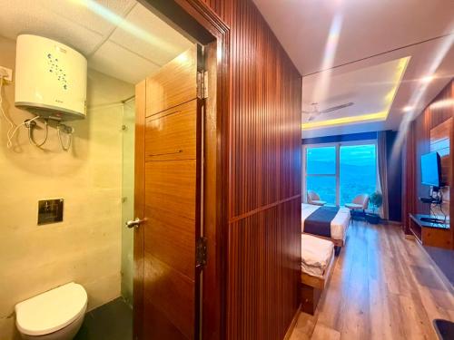 a bathroom with a toilet and a bedroom at Pine View Luxury Resort With Mountain View & Premium Rooms Mussoorie in Mussoorie