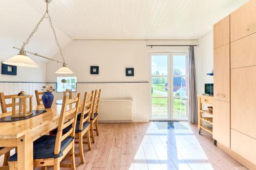 a kitchen and dining room with a wooden table and chairs at Reetdachhaus Sünsbarg in Simonsberg