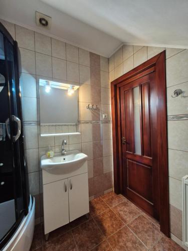 a bathroom with a sink and a mirror and a door at PENSIUNEA BIO in Coltău