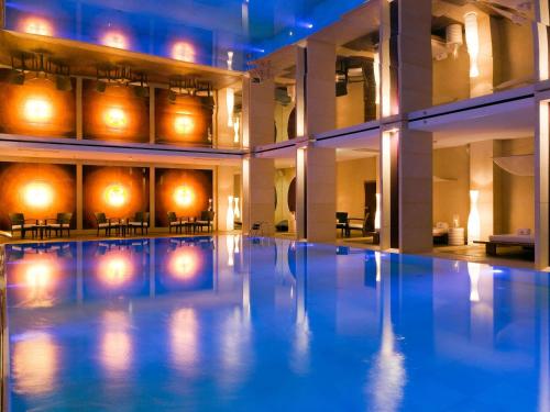a large swimming pool in a building with lights at Sofitel Warsaw Victoria in Warsaw