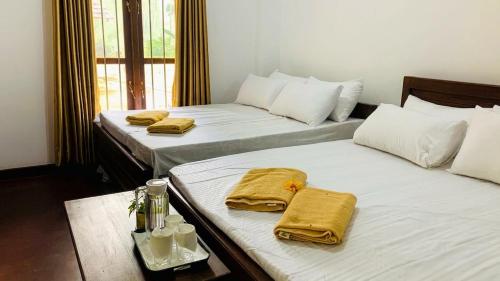 two beds in a room with towels on them at Mist Mountain Hiking Base in Pimbura