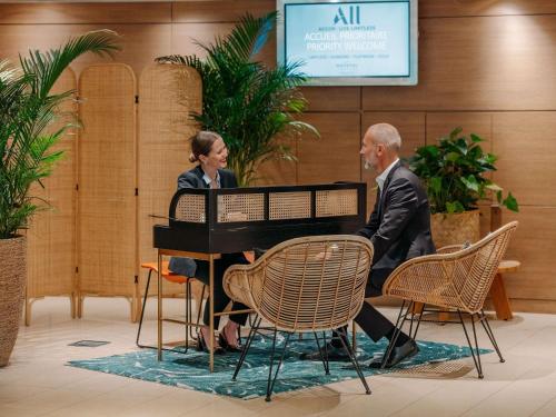 a man and woman sitting at a piano in a lobby at Novotel Paris Centre Tour Eiffel in Paris