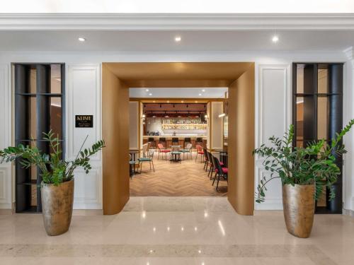 a lobby with two potted plants and a bar at Mövenpick Hotel Budapest Centre in Budapest