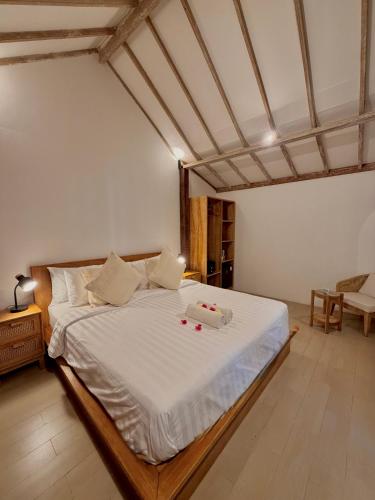 a bedroom with a large bed with white sheets at Kalua Boutique Bungalows in Gili Trawangan