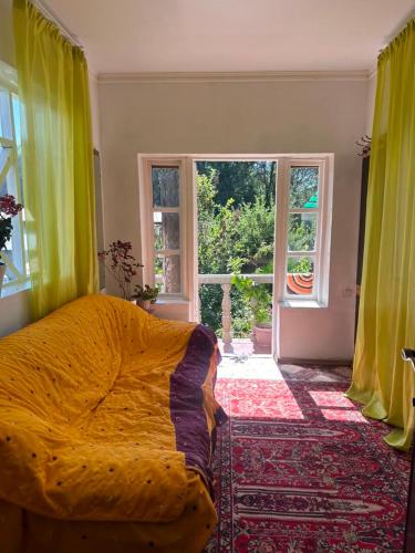 a bedroom with a bed with a yellow comforter and a window at House in the forest in Tyup