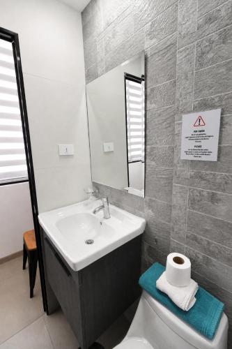 a bathroom with a sink and a toilet and a mirror at Apart Hotel Regata Iquique in Iquique