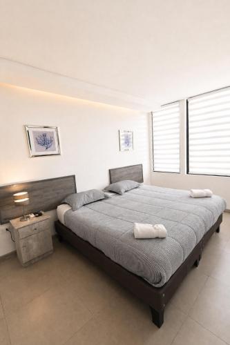 a bedroom with a large bed with two towels on it at Apart Hotel Regata Iquique in Iquique