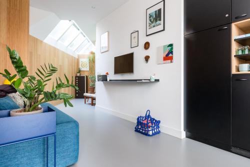 a living room with a blue couch and a tv at Kith & Kin Boutique Apartments in Amsterdam