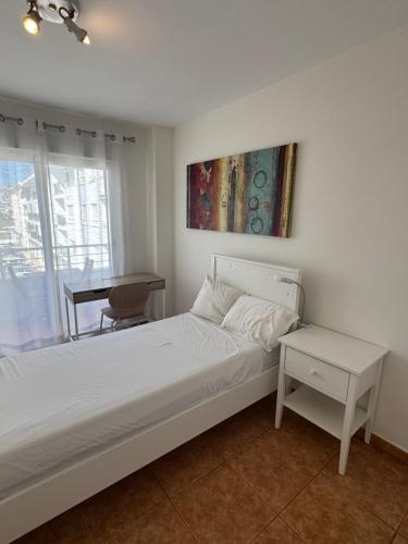 a white bedroom with a bed and a desk at WohnungAltea - Kirche, Berge, am Meer in Altea