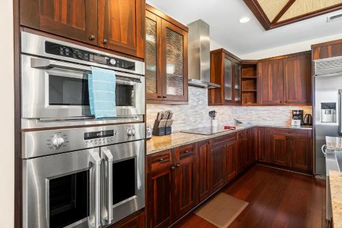 a kitchen with wooden cabinets and stainless steel appliances at Holua Kai 21 in Kailua-Kona