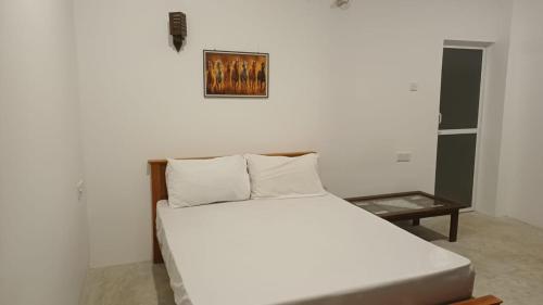 a white bed in a room with a picture on the wall at villa calm haven in Unawatuna