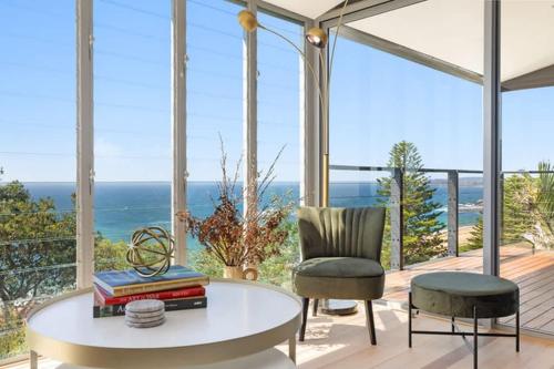 a living room with a table and a chair and the ocean at Sandcastle by Coast Hosting in Wamberal