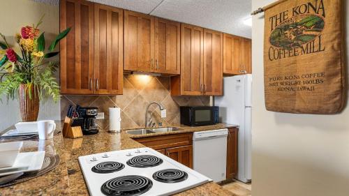 a kitchen with a stove and a white refrigerator at Kona Pacific C520. in Kailua-Kona