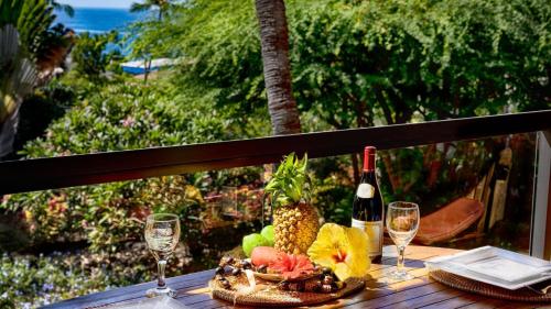a table with a plate of fruit and a bottle of wine at Kona Pacific C520. in Kailua-Kona