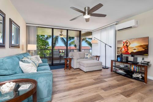 a living room with a blue couch and a ceiling fan at Kona Pacific D622 in Kailua-Kona