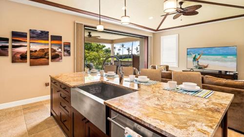 a kitchen with a sink and a living room at Holua Kai 6 in Kailua-Kona