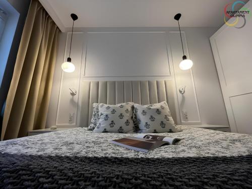 a bedroom with a bed with a book on it at Apartament Olimpia in Lębork