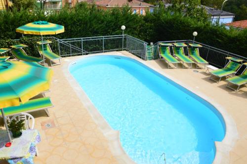 a swimming pool with chairs and umbrellas next to at Hotel Garden Ristorante in Tabiano