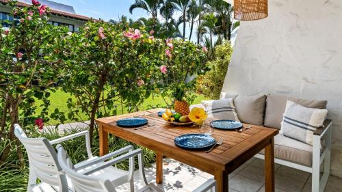 a wooden table with a bowl of fruit on a patio at Casa de Emdeko 124 in Kailua-Kona