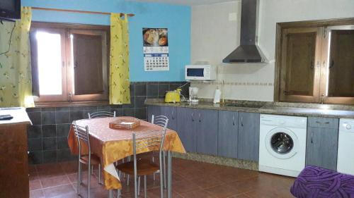 eine Küche mit einem Tisch und einer Waschmaschine in der Unterkunft Apartamentos Alejandra in Gargantilla