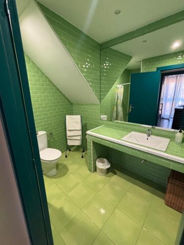 a green bathroom with a sink and a toilet at El encanto de un pueblo in Grajal de Campos