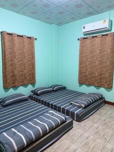 three empty mattresses in a room with curtains at เพียงภูโฮมสเตย์ in Sattahip