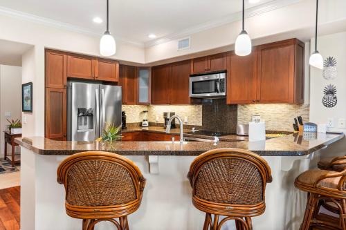a kitchen with wooden cabinets and a large island with bar stools at Halii Kai 20F in Waikoloa