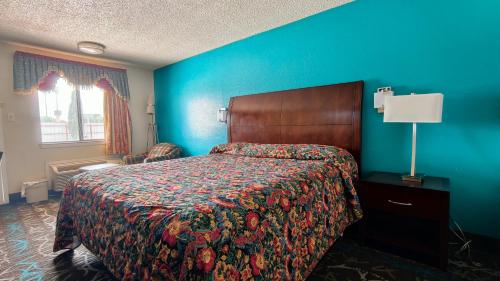 a bedroom with a bed and a blue wall at Deluxe Inn By Capital O Odessa I-20 in Odessa