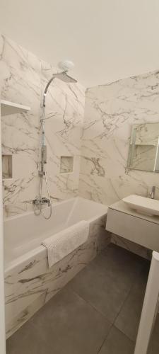 a white bathroom with a tub and a sink at Les chambres de Dolce in Bandol