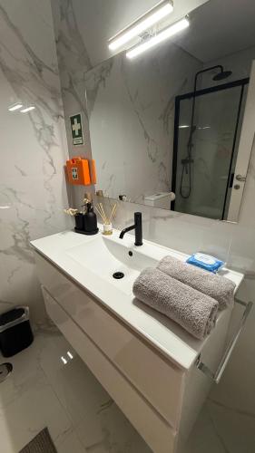 a white bathroom with a sink and a mirror at Apartamento de Real in Braga