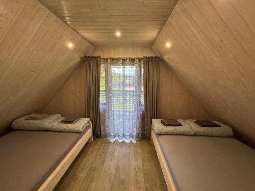 two beds in a small room with a window at Pakarklių sodyba in Anykščiai