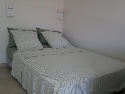 a bed with white sheets and pillows in a room at Studios Saint Mau 4 in Saint-Maurice-de-Gourdans