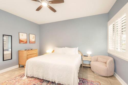 a bedroom with a bed and a chair and a ceiling fan at Sunny Side Cottages in Dunedin