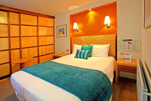 a hotel room with a bed with a blue blanket at Britannia Hotel Bolton in Bolton